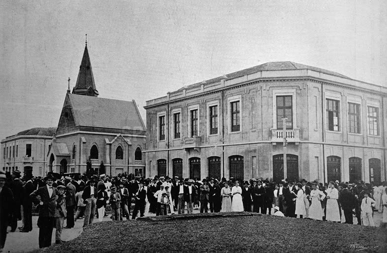 Fotografia de 1917 com a multidão na inauguração da Vila Maria Zélia, capela e prédio principal ao fundo
